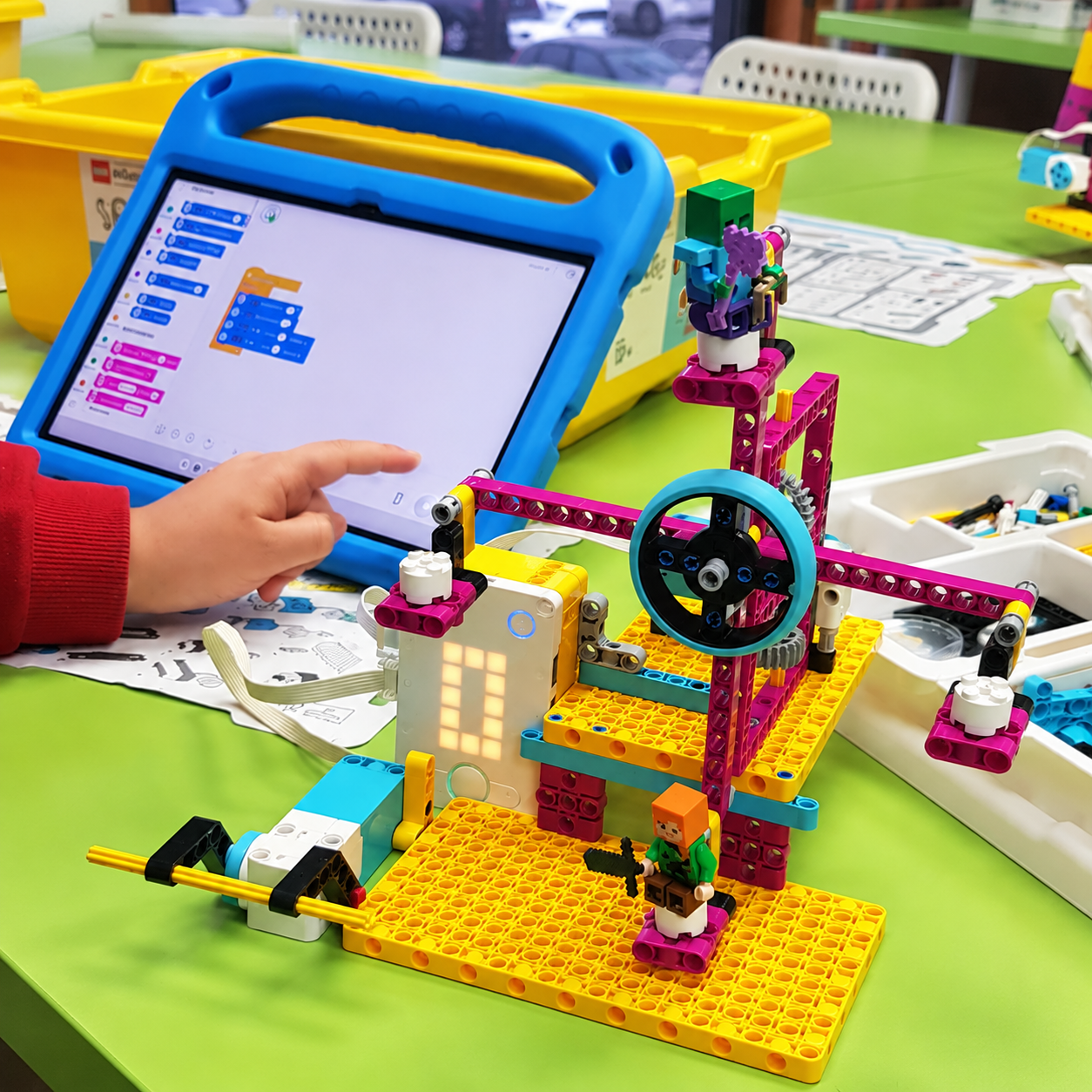 Mano de un alumno programando un robot educativo LEGO Spike con una tableta durante un taller de robótica de Astrobots.